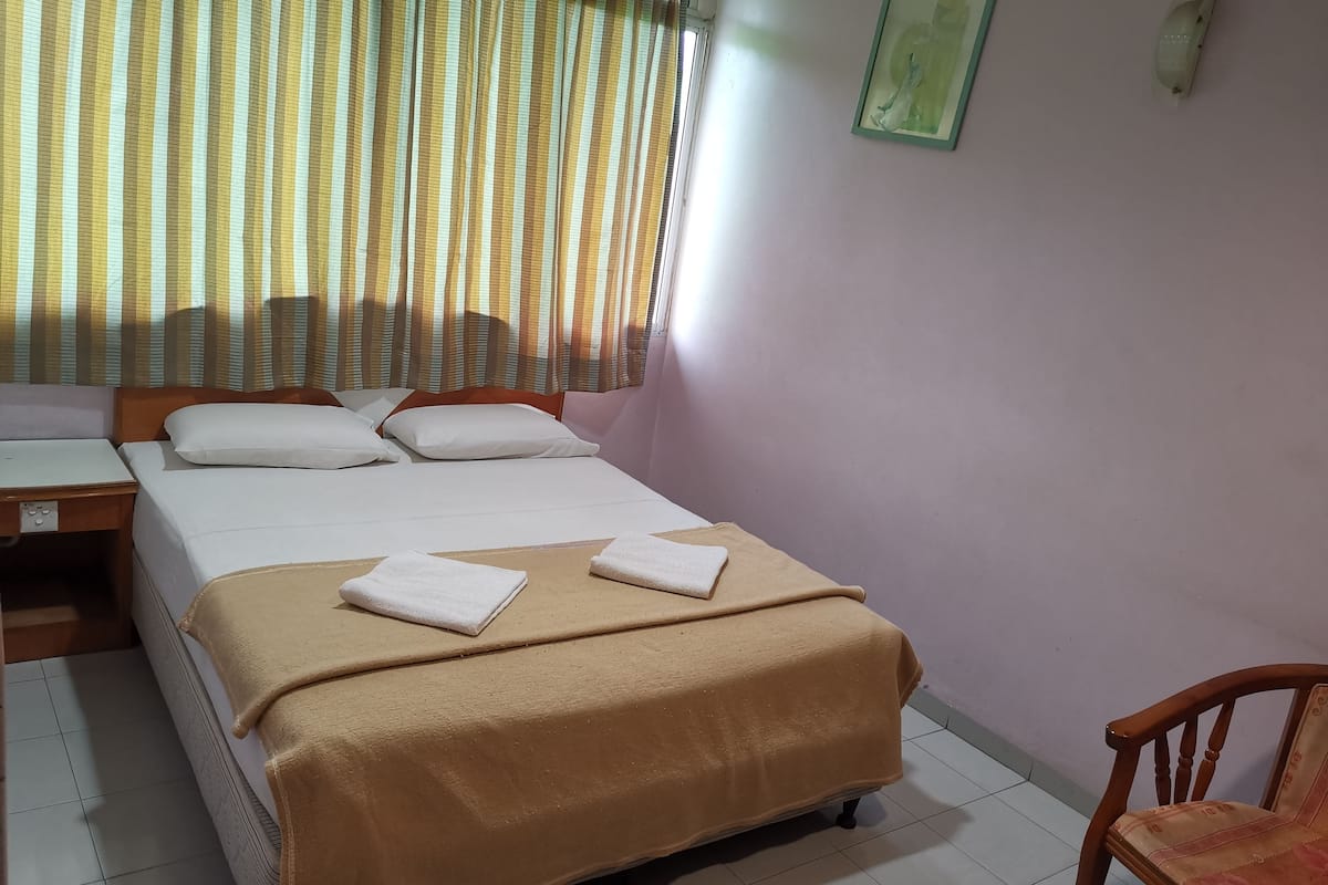 A neatly arranged hotel room with a bed, a desk, and a chair.