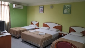Una camera d'albergo con due letti, una scrivania, una sedia e una televisione.