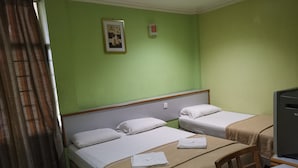 Una stanza con due letti, una scrivania, una sedia, una televisione e un quadro appeso al muro.