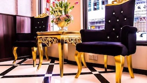 A luxurious room with a checkered floor, a black velvet chair, a gold table, and a vase of flowers. - Kimberley Hotel Georgetown (George Town)