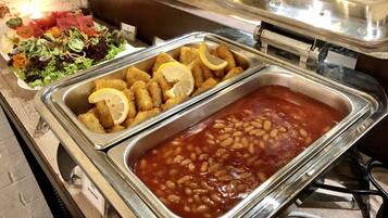 A buffet with various dishes including baked beans and lemon slices.