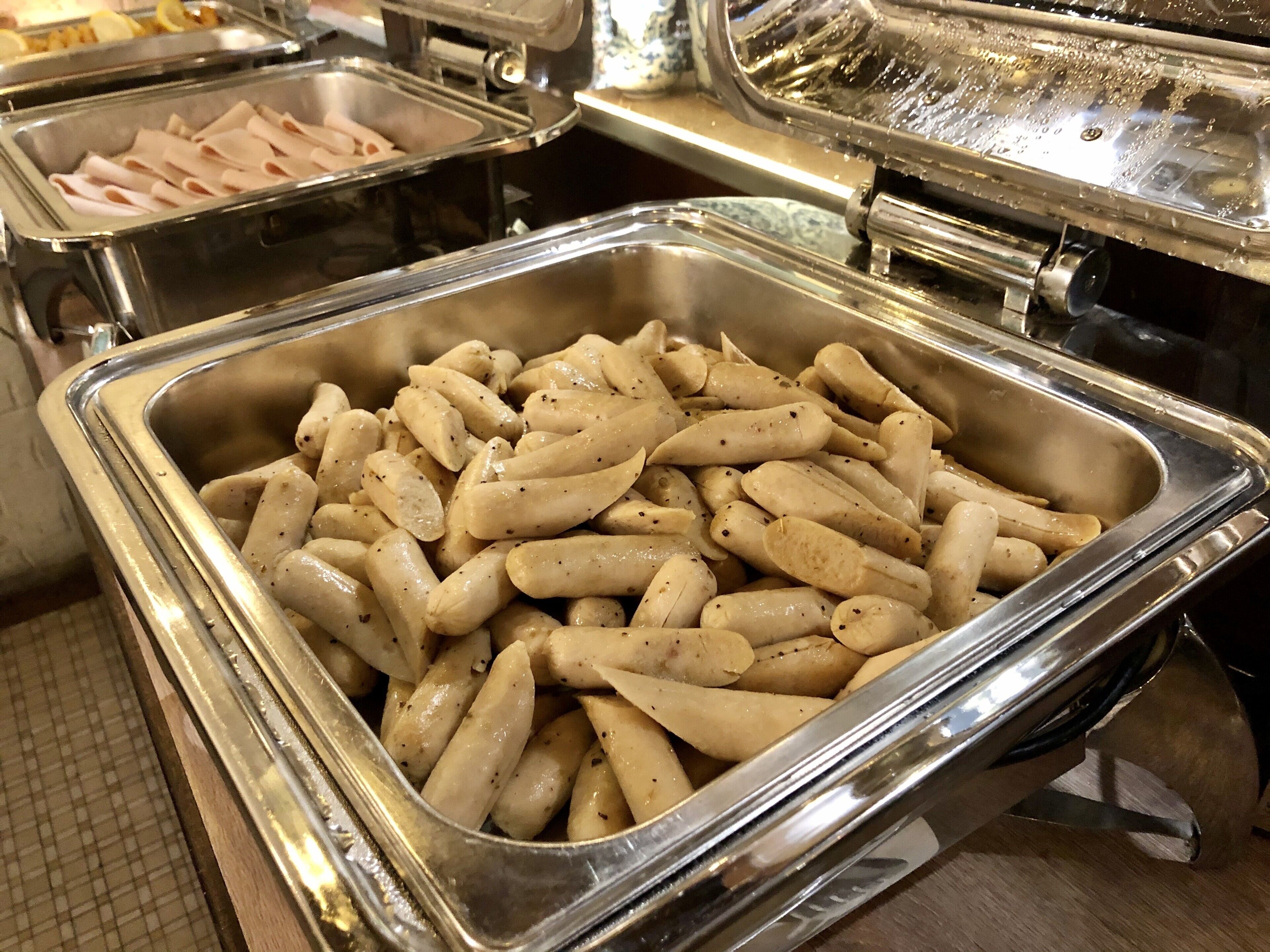 Un buffet proposant une variété de plats, notamment des viandes en tranches et des pâtes.
