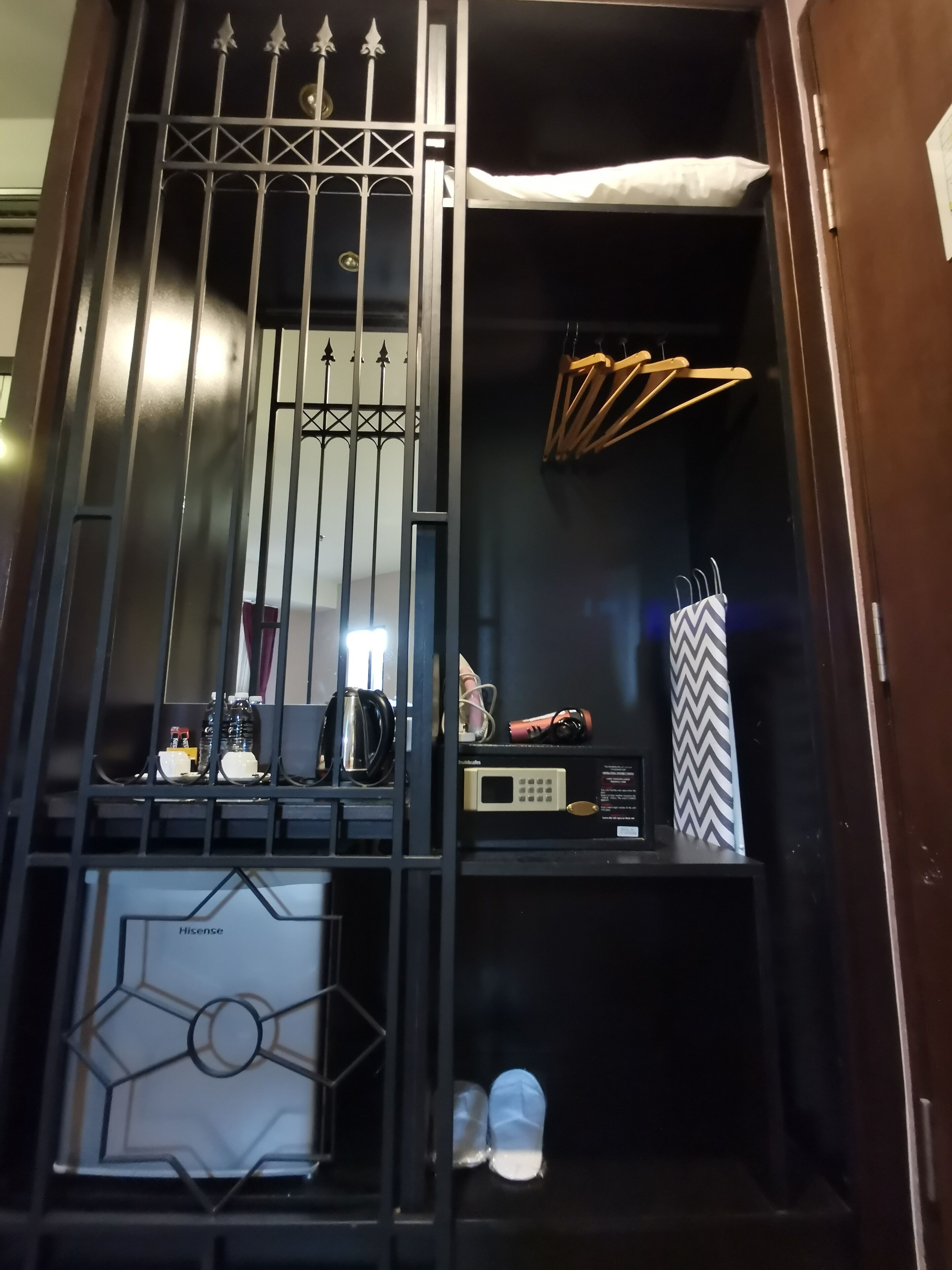 A wardrobe with a mirrored door, a small shelf with a microwave, and a hanging rack with clothes.