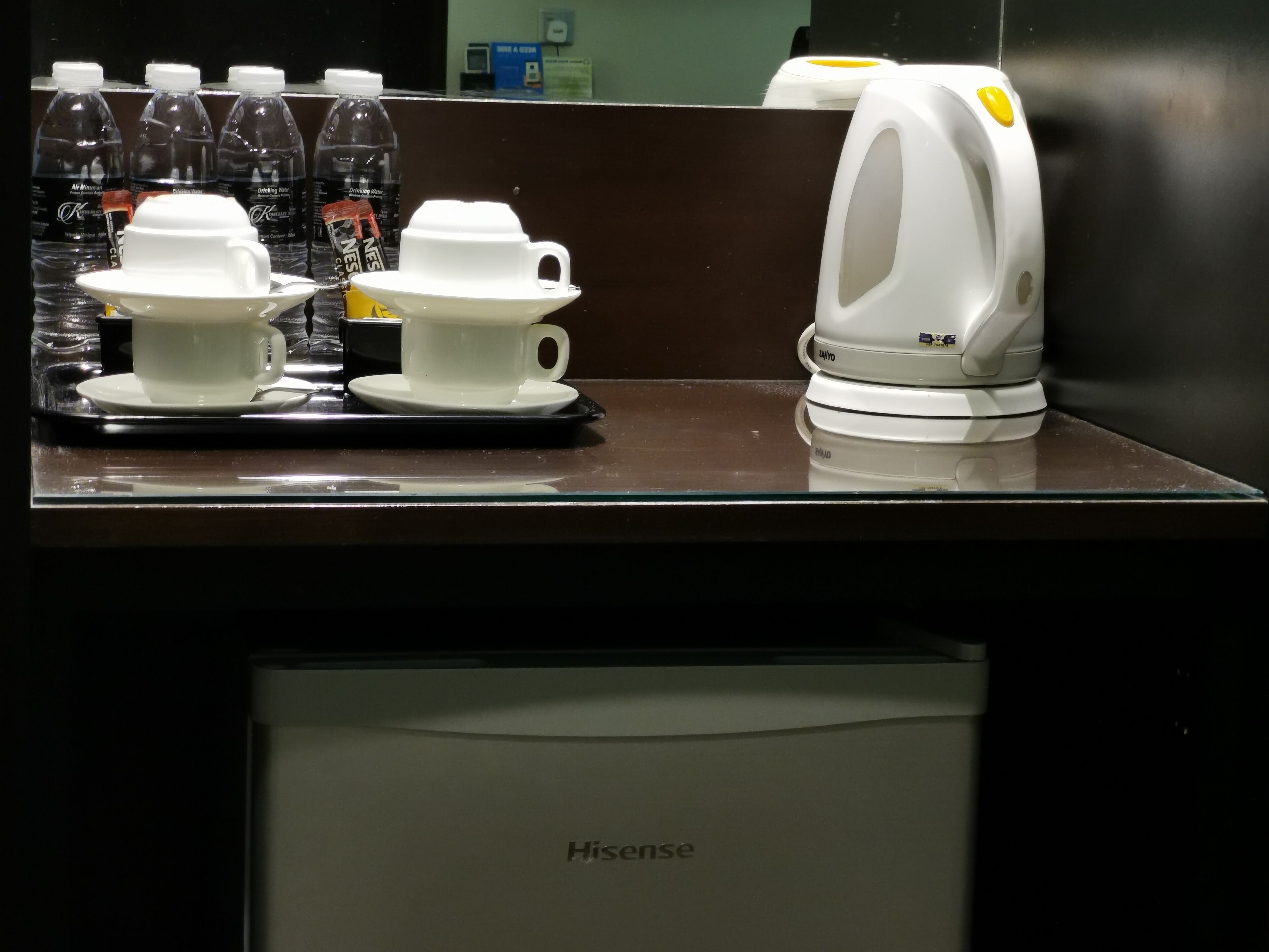 A coffee station with disposable cups and a coffee machine, and a refrigerator labeled "Hisense" below.