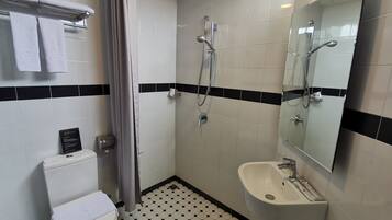 Un baño con inodoro, ducha, lavabo y espejo.