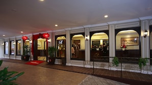 A hotel lobby with a red carpet, potted plants, and a reception area with a TV screen. - Kimberley Hotel Georgetown (George Town)