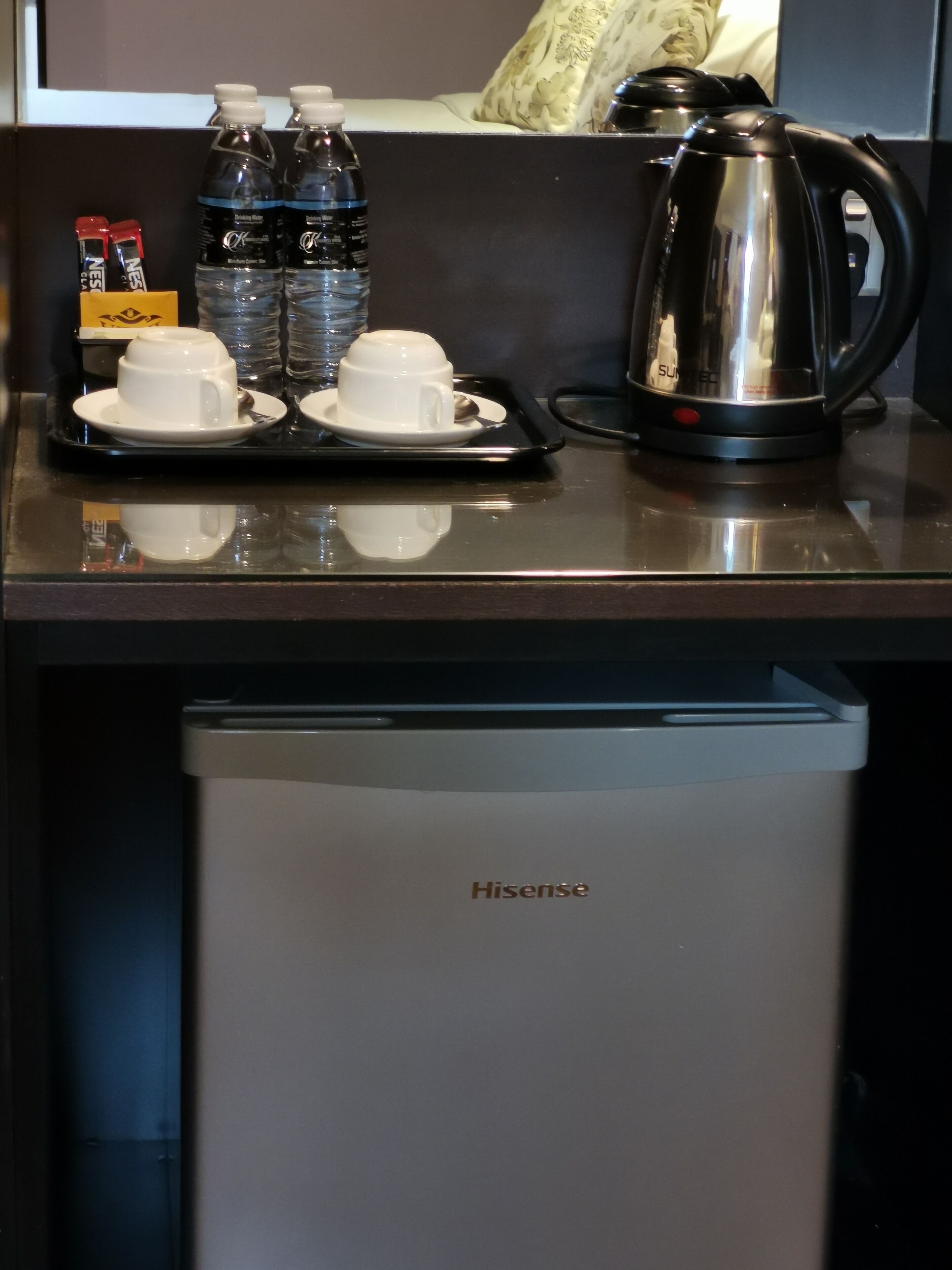 Eine Küchenzeile mit einem Hisense-Kühlschrank, einer Kaffeemaschine und Wasserflaschen auf einem Tablett mit Tassen.