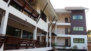A multi-story building with balconies, a covered outdoor area, and a parking lot. - Baan Nai Wiang (Nan)