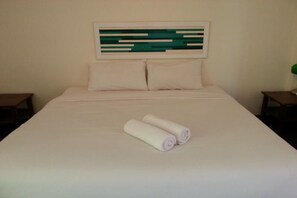 A neatly made bed with white linens and two rolled towels on it. - Baan Nai Wiang (Nan)