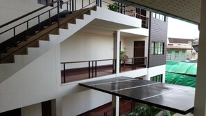 A multi-level building with a staircase, a ping pong table, and a balcony with plants. - Baan Nai Wiang (Nan)