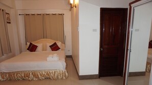 Une chambre d’hôtel avec un lit, des rideaux, une porte en bois et un miroir.