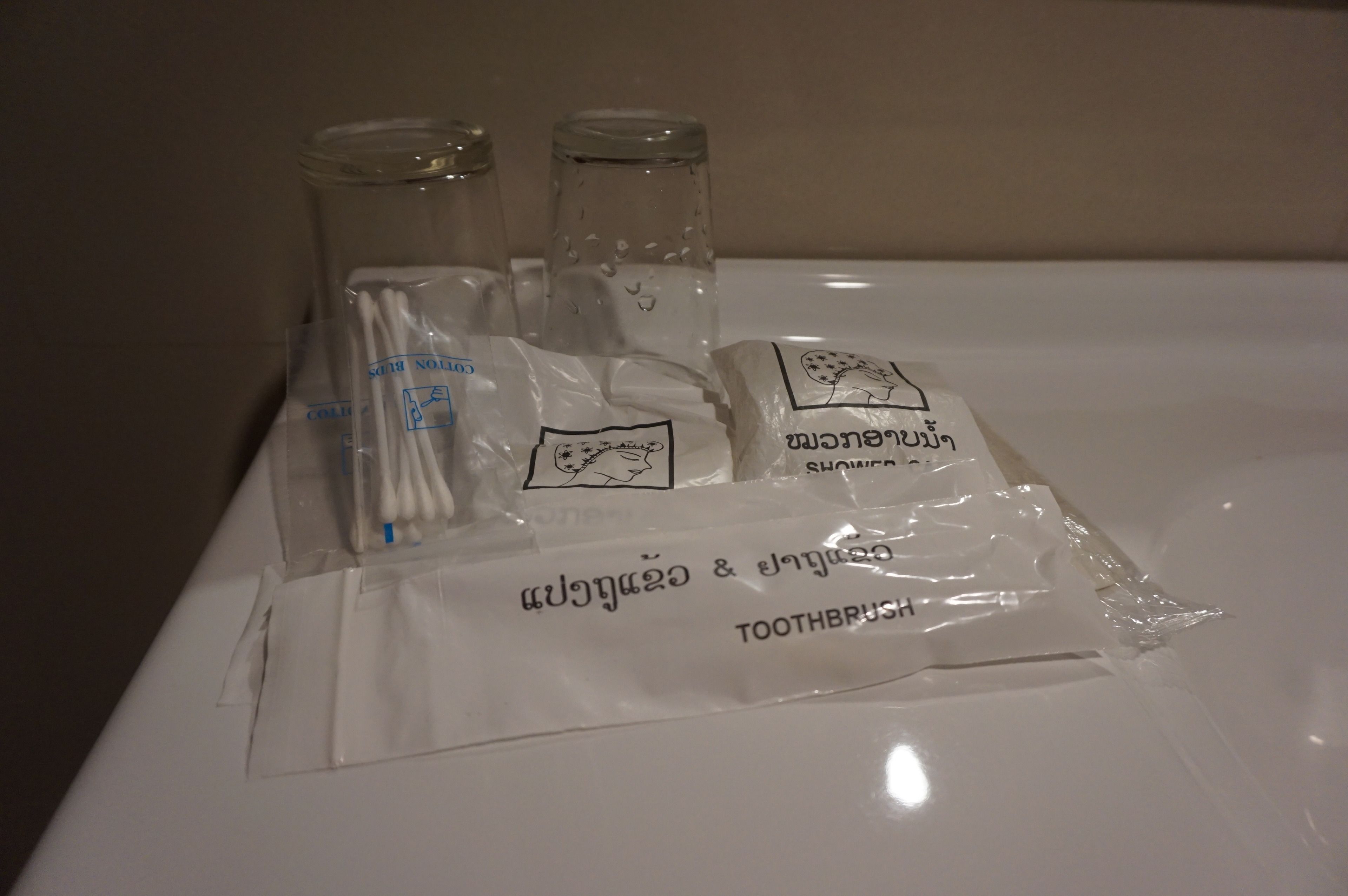 Une salle de bain avec un comptoir blanc, un pot en verre, une brosse à dents et un sac contenant des articles de toilette.