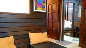 A wooden room with a bed, two pillows, and a colorful artwork on the wall. - TnT Novelty House (Teluk Intan)