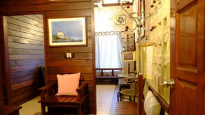 A wooden interior with a bench, a table, a hanging light fixture, and a framed picture on the wall. - TnT Novelty House (Teluk Intan)