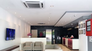 A modern reception area with a reception desk, two sofas, a coffee machine, and a TV screen. - Tumike Hotel Bentong (Bentong)