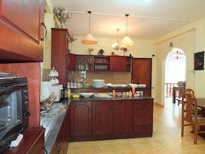 A kitchen with wooden cabinets, a stove, and a dining area with a table and chairs.