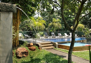 A pool area with lounge chairs, a small pool, and surrounding greenery.