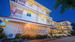 A multi-story hotel with a brick facade, balconies, and parked cars. - Nuntiya Terrace (Udon Thani)
