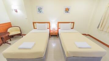 A hotel room with two single beds, a small round table, and a chair.