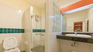 A bathroom with a toilet, a glass shower enclosure, and a sink with a mirror above it. - Nuntiya Terrace (Udon Thani)