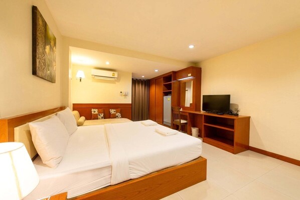 Una habitación de hotel con una cama grande, televisión, armario y aire acondicionado.