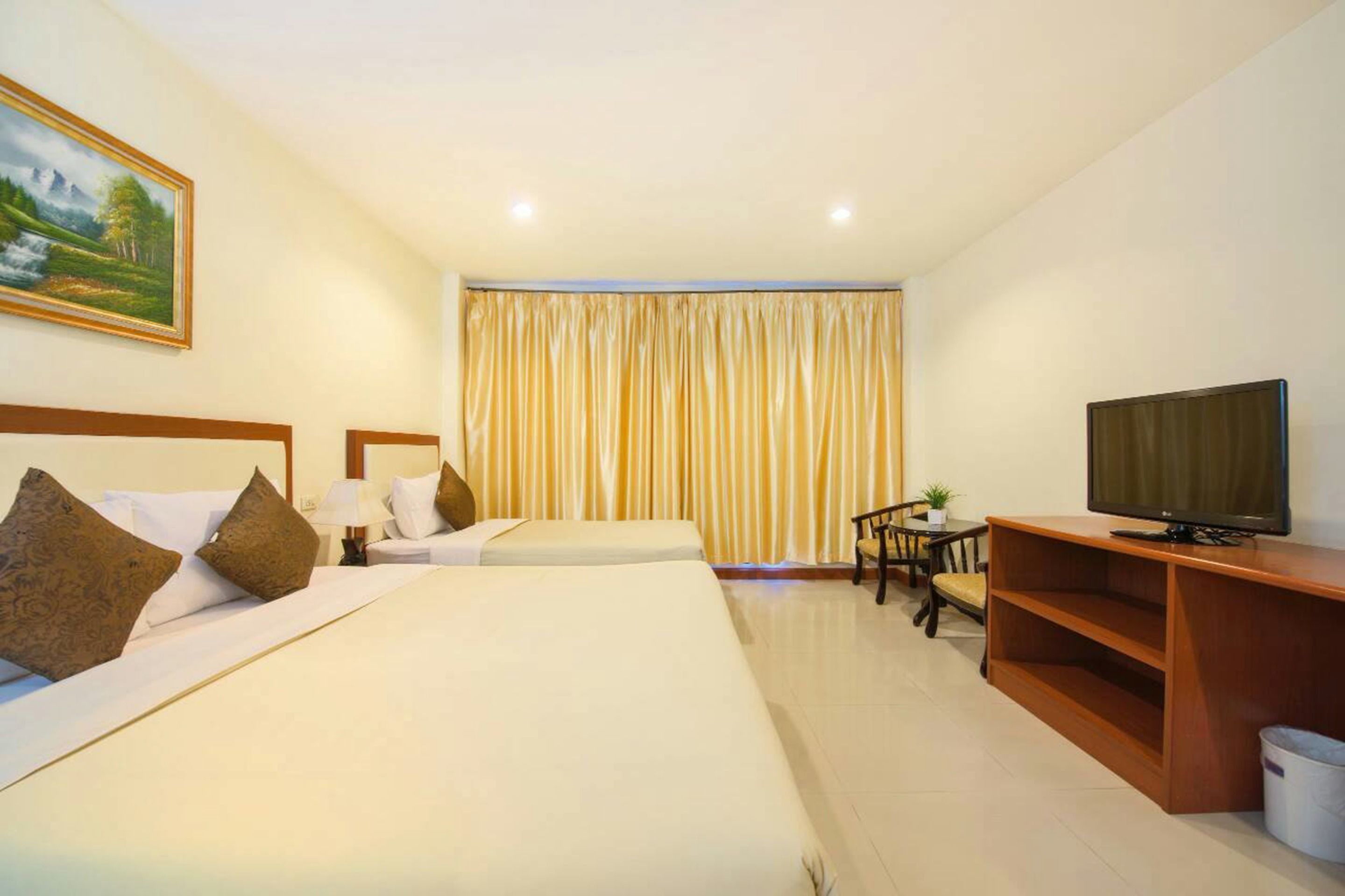A hotel room with two beds, a television, a desk with a chair, and a large window with curtains.