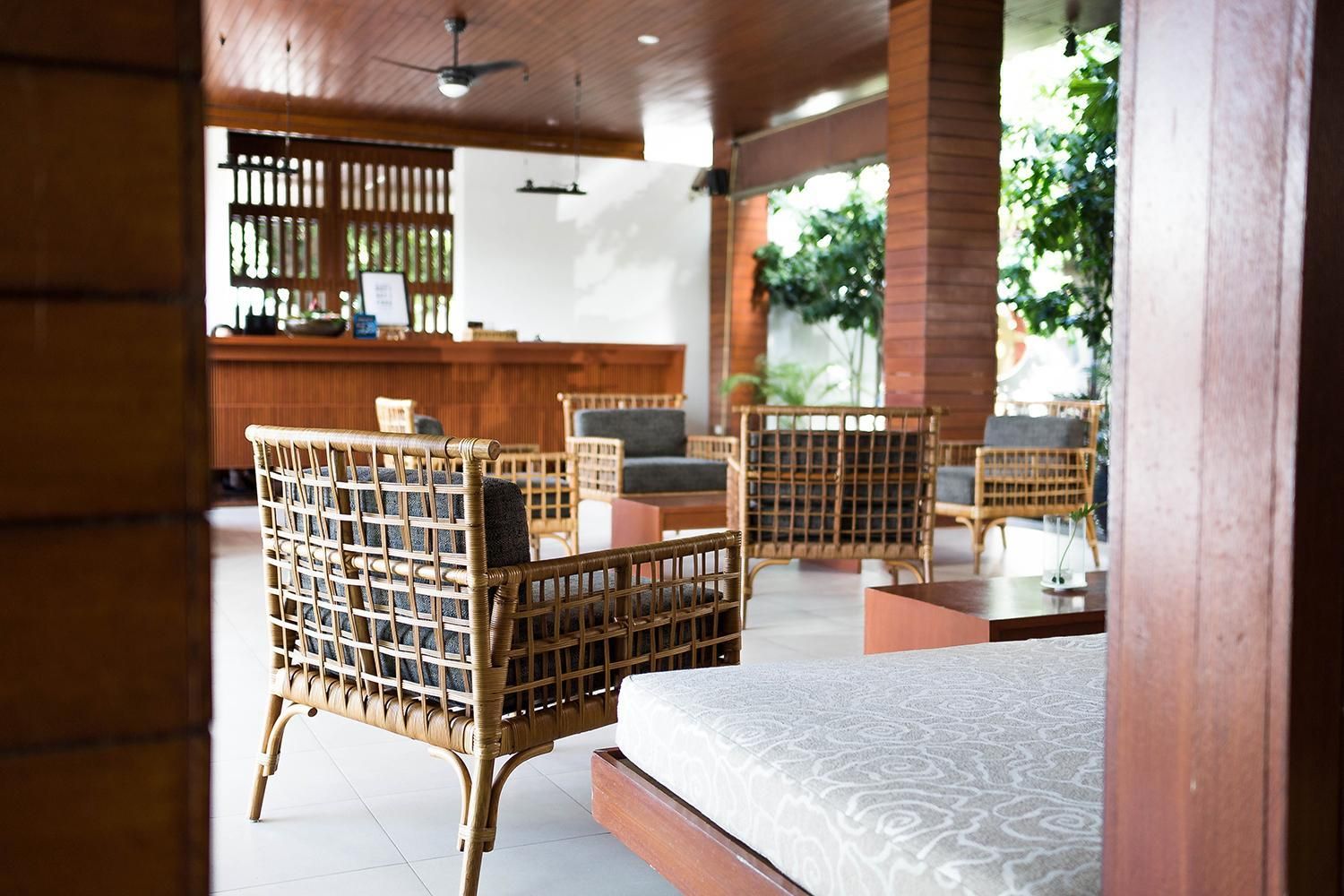 A room with wicker furniture, a bed, and a reception area with a counter.