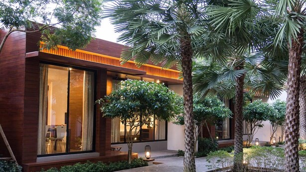 A modern house with large windows, a wooden exterior, and a well-maintained garden with palm trees and shrubs. - Tri-Shawa Resort (Prachuap Khiri Khan)