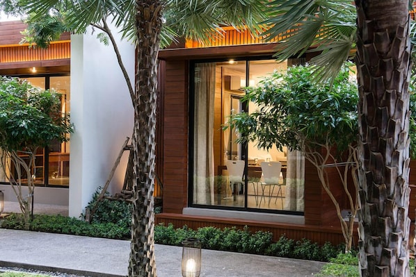 A modern building with large windows, a wooden facade, and surrounding greenery.