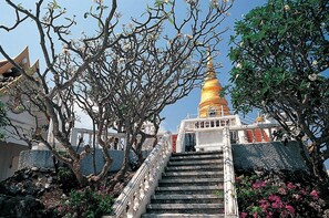 A staircase leading to a golden stupa with a railing, surrounded by trees and flowers. - Tri-Shawa Resort (Prachuap Khiri Khan)