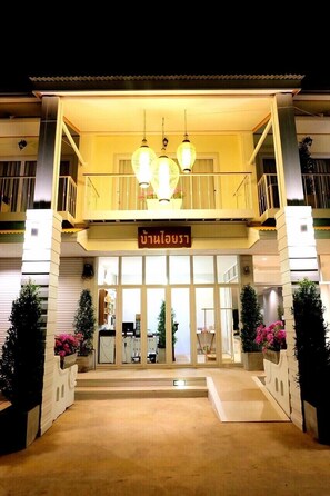 A hotel entrance with a balcony, a sign, and potted plants. - Baan Iyara Boutique City Hotel (Nan)