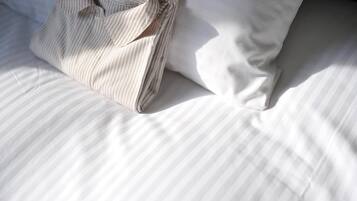 A neatly made bed with striped bedding and a folded shirt on it.