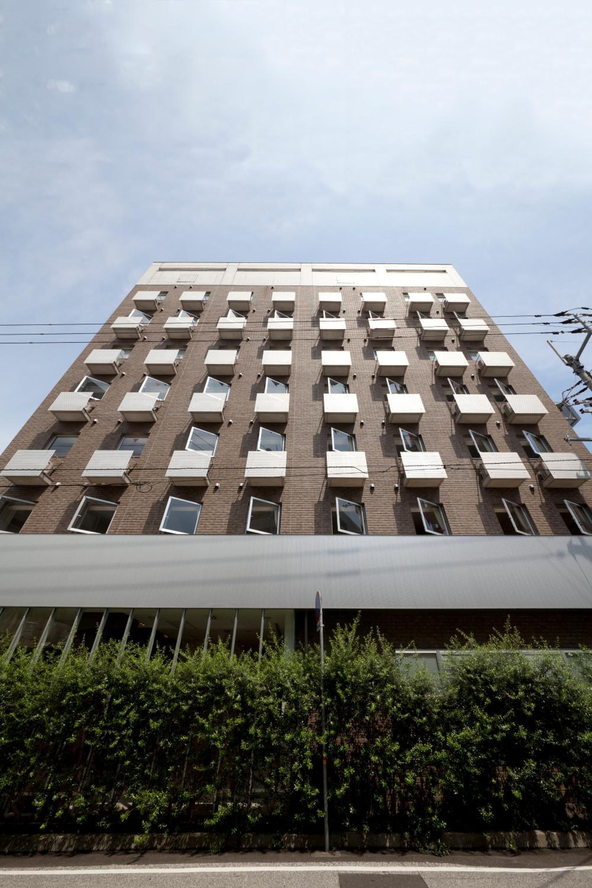 Un immeuble à plusieurs étages, doté d’une façade uniforme, avec des fenêtres et des balcons régulièrement espacés.