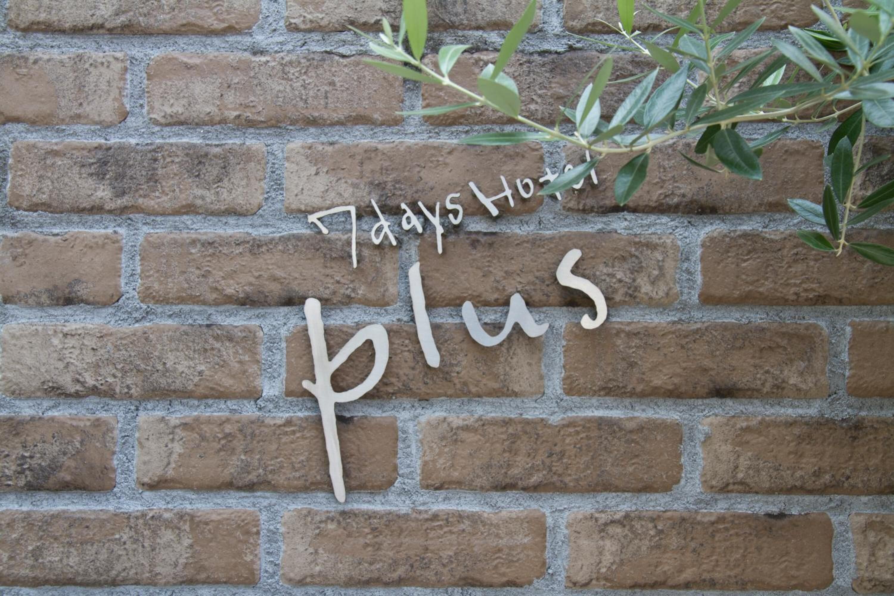 A brick wall with a sign that reads "7 days Hotel Plus."