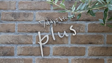 A brick wall with a sign that reads "7 days Hotel Plus."