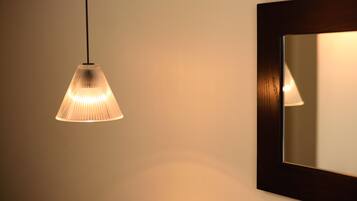 A pendant light fixture with a ribbed design hanging from the ceiling, a wall-mounted mirror, and a portion of a dark-framed picture frame.
