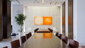 A conference room with a long table, chairs, a clock, and a large abstract painting on the wall. - 7 Days Hotel Plus (Kochi)