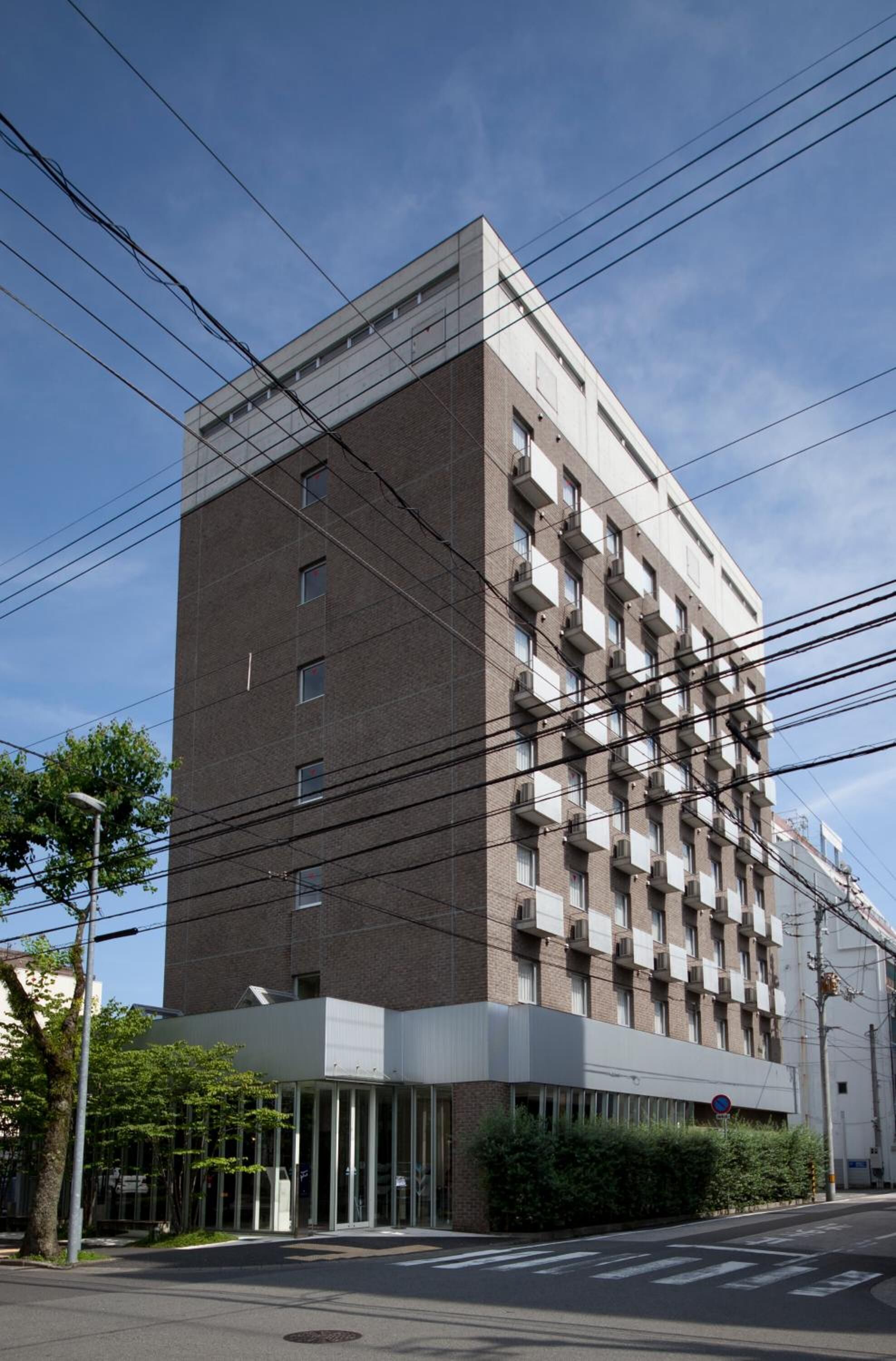 A multi-story building with a modern design, featuring a mix of brick and white exterior, and a glass entrance.