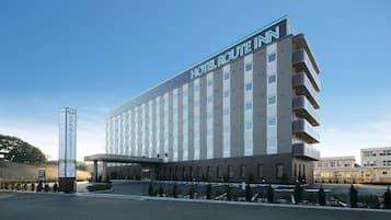 Experience the Hotel Route Inn's sleek, multi-story design with a prominent entrance and covered walkway.