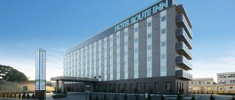 A multi-story hotel with a modern design, featuring a prominent sign for Hotel Route Inn.