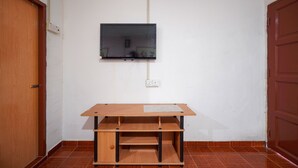 A room with a wooden desk, a mounted TV, and a tiled floor. - OYO 89646 Panvill Resort (Pangkor Island)