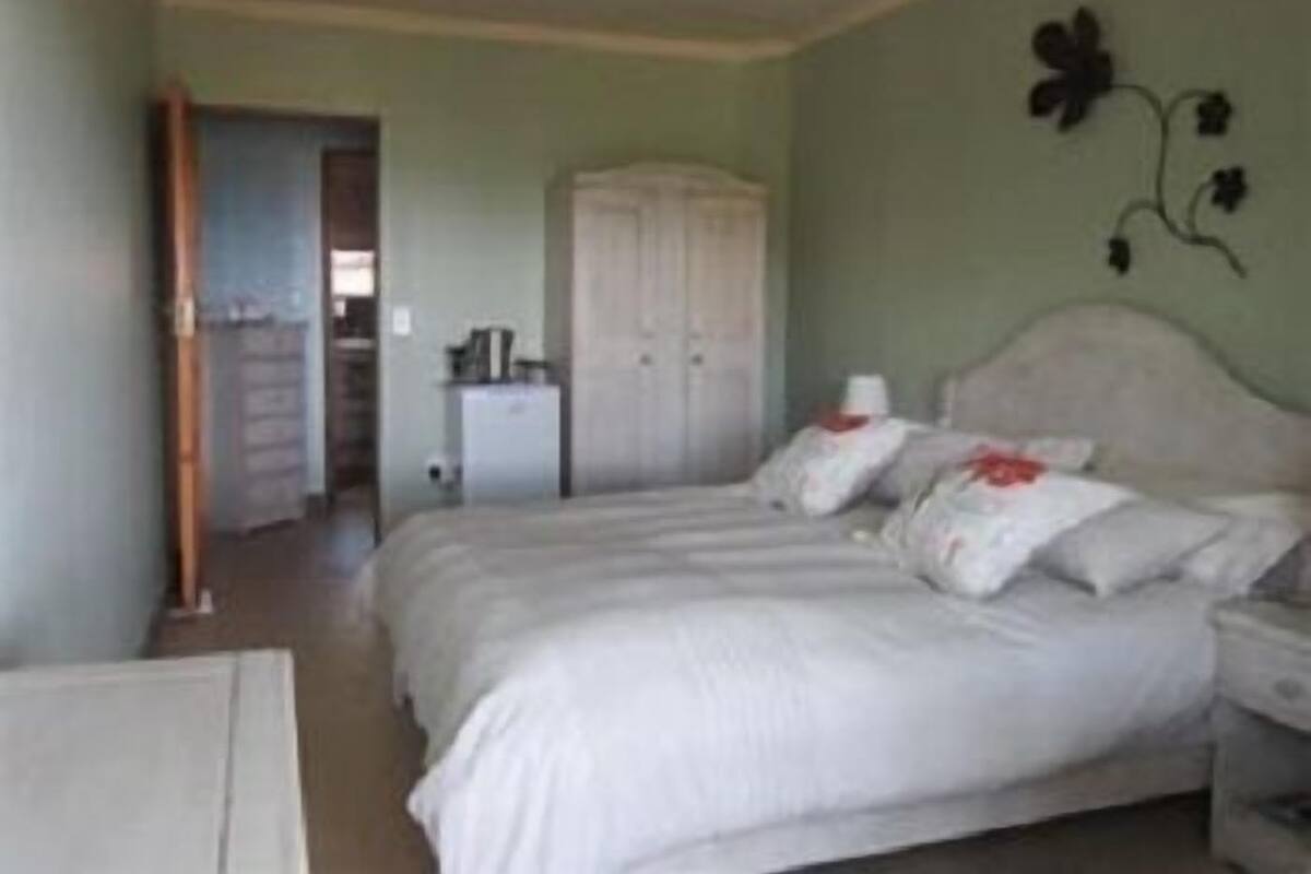 A bedroom with a bed, a nightstand, a wardrobe, and a small table.