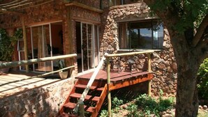A stone building with a wooden staircase leading to a deck area. - Marula Cottage (Thabazimbi)