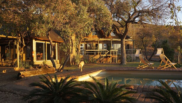 A rustic lodge with a stone facade, a pool, and outdoor seating. - Marula Cottage (Thabazimbi)
