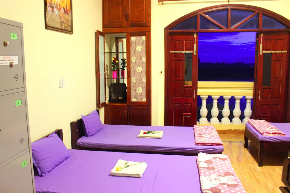 Ein Zimmer mit zwei Betten, einem Holzschrank, einem Spiegel und einem Balkon mit Blick auf den Nachthimmel.