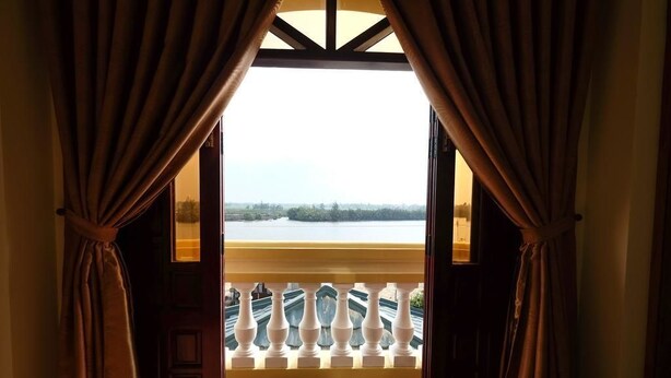 An open door with curtains, leading to a balcony with a railing. - River Park Homestay and Hostel (Da Nang)