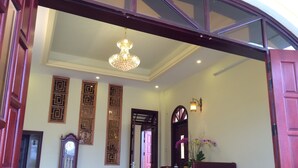 A spacious lobby with a chandelier, a grandfather clock, and a dining area with a table and chairs. - River Park Homestay and Hostel (Da Nang)