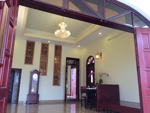 A spacious lobby with a chandelier, a grandfather clock, and a dining area with a table and chairs.