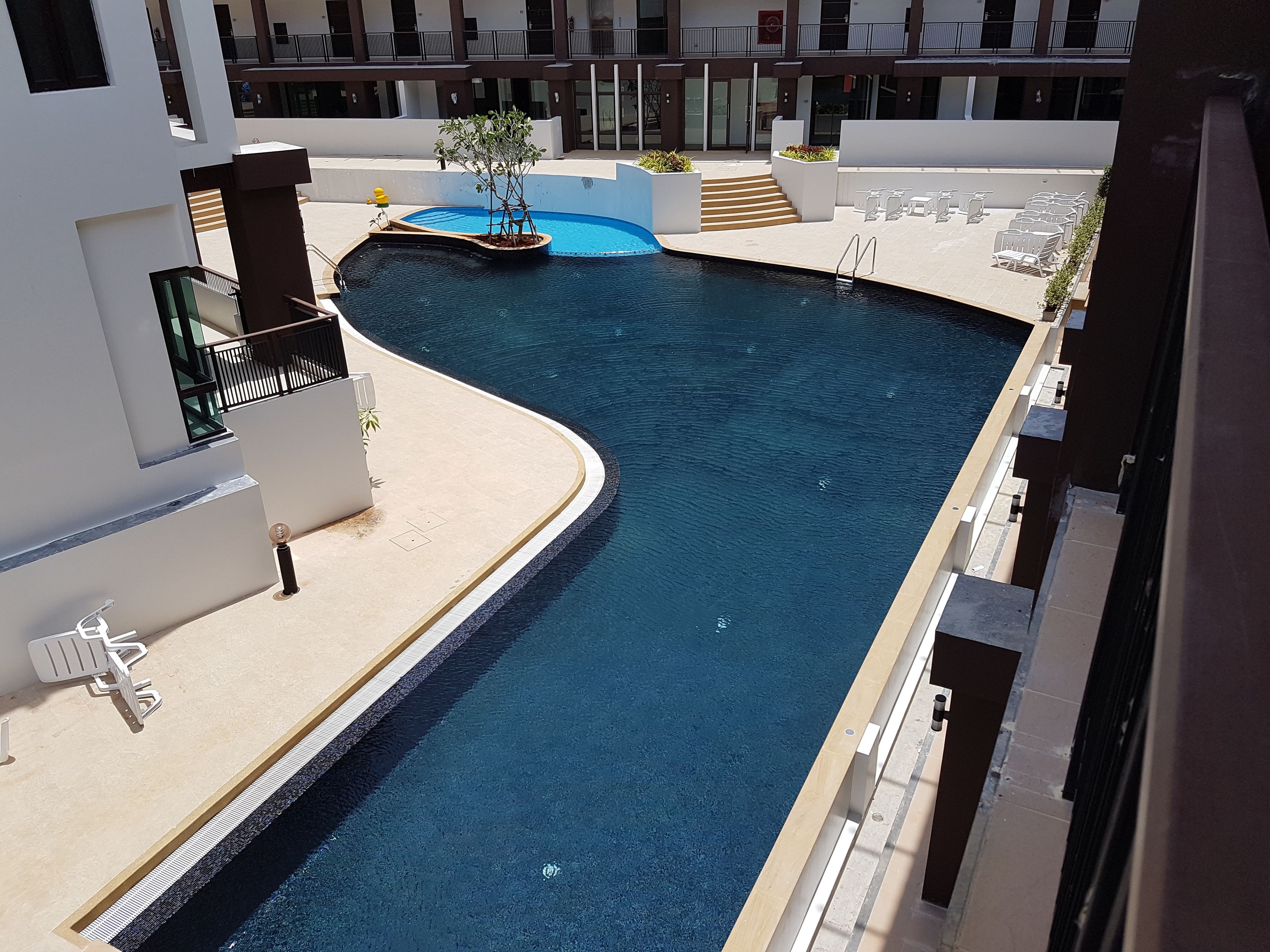 Un hôtel moderne doté d’une piscine, d’un espace extérieur aménagé et d’un escalier menant aux étages supérieurs.
