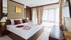 A hotel room with a large bed, two bedside tables, a TV, and a window with curtains. - The Lai Thai Luxury Condominiums (Krabi)